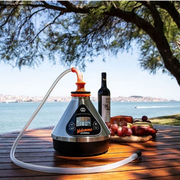 The Volcano Hybrid on a table outdoors, with hose attachment equipped